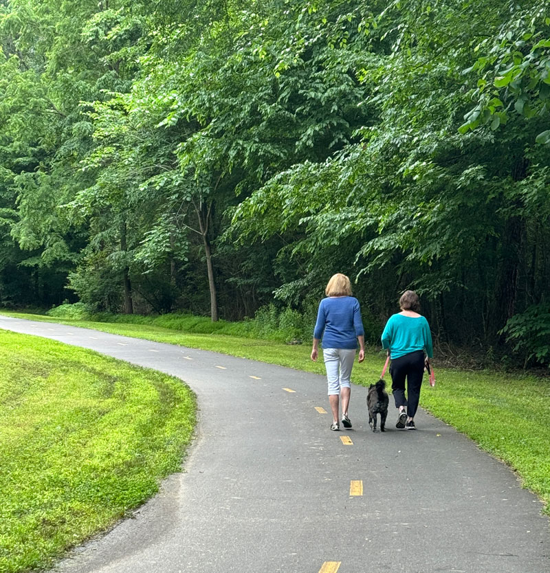 Therapist walking with a client on the Raleigh Greenway system